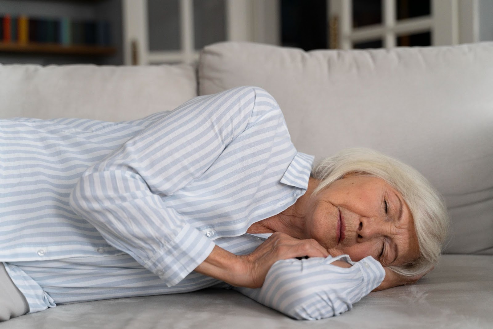 An older woman is sleeping on a couch